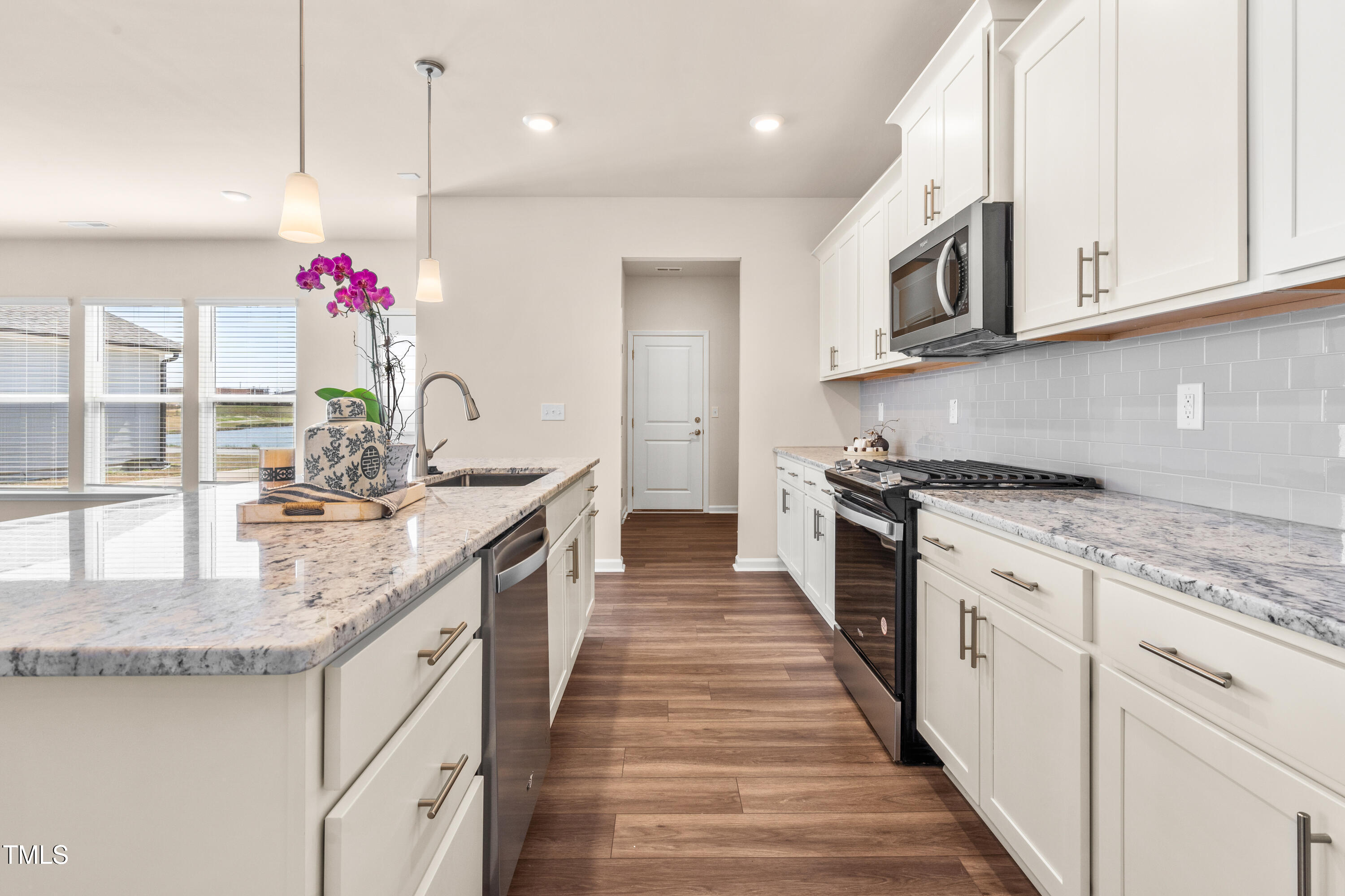 5800 Agrinio Way Raleigh, NC 27603 - Photo 10 of 38 a kitchen with granite countertop a white stove top oven sink and cabinets