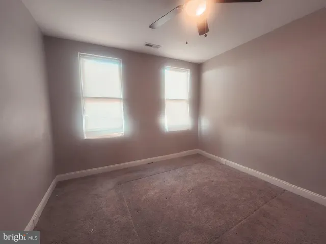 an empty room with windows and chandelier fan