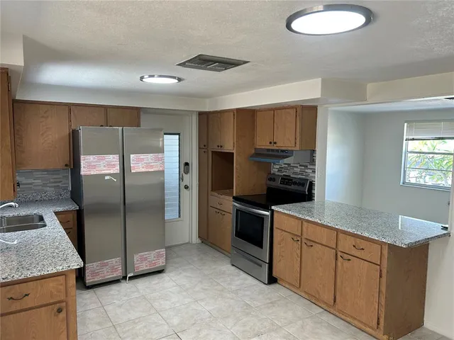 a kitchen with stainless steel appliances granite countertop a refrigerator a sink a stove and oven