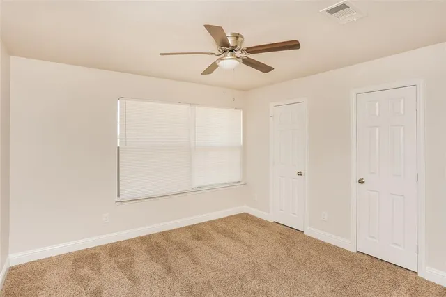 an empty room with a window and a fan