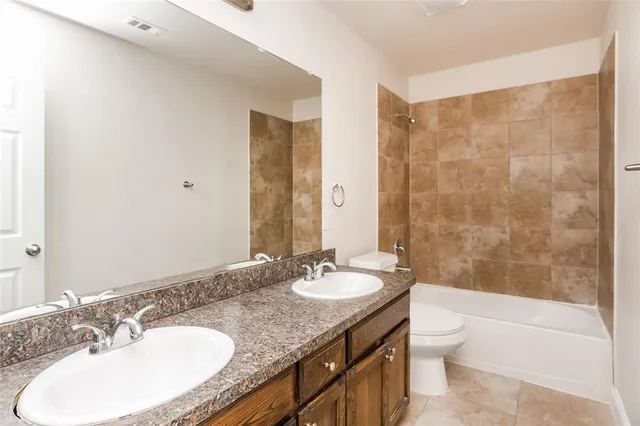a bathroom with a granite countertop sink a toilet a mirror and shower