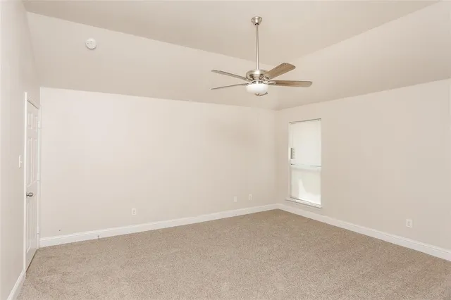 an empty room with a ceiling fan and a window