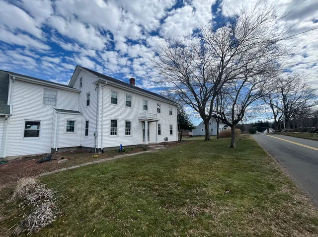 a big white house with a big yard and large trees