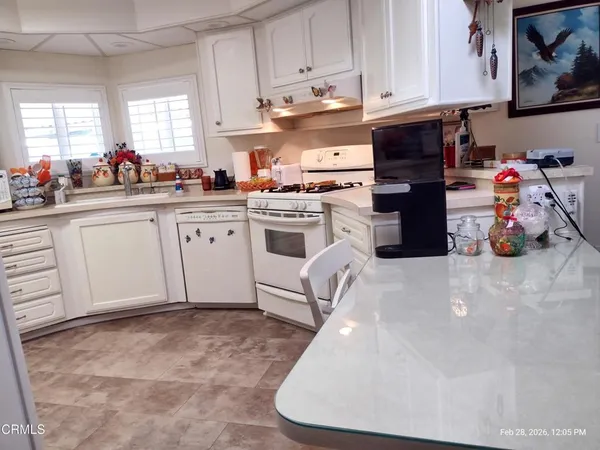 a kitchen with stainless steel appliances granite countertop a sink a stove and white cabinets
