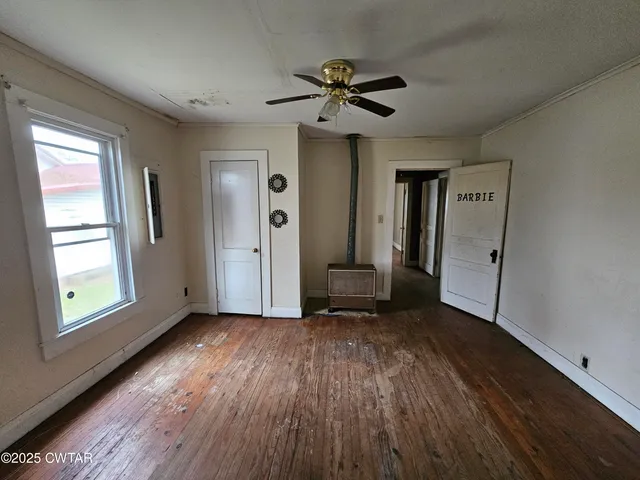 a view of an empty room with a window and wooden floor