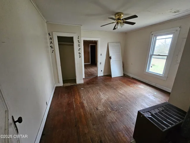 a view of an empty room with a window and wooden floor