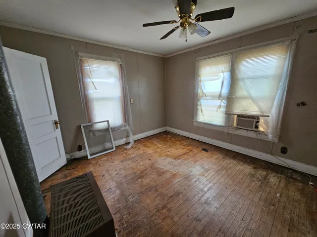 a view of an empty room with a window and wooden floor