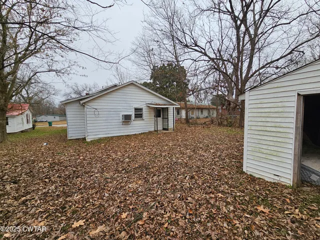 a backyard of a house with wooden fence and large tree