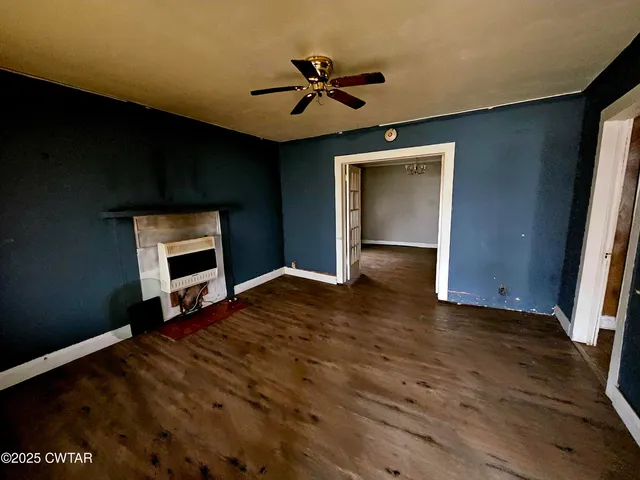 a view of an empty room with a ceiling fan and wooden floor