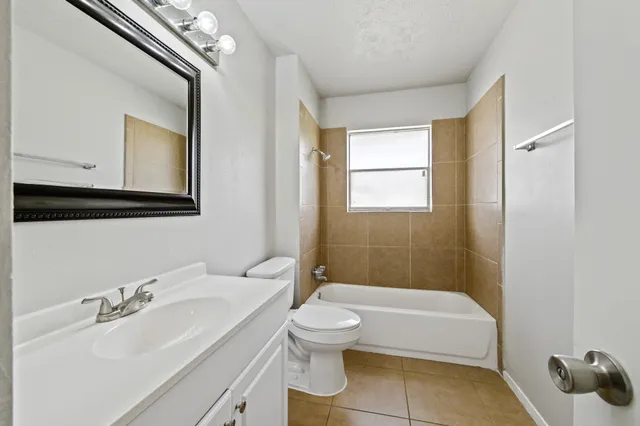 a bathroom with a granite countertop sink toilet a mirror and bathtub