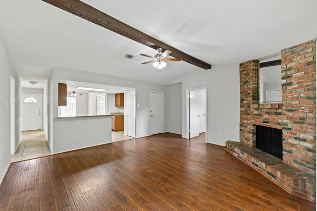 a view of an empty room with wooden floor and a fireplace