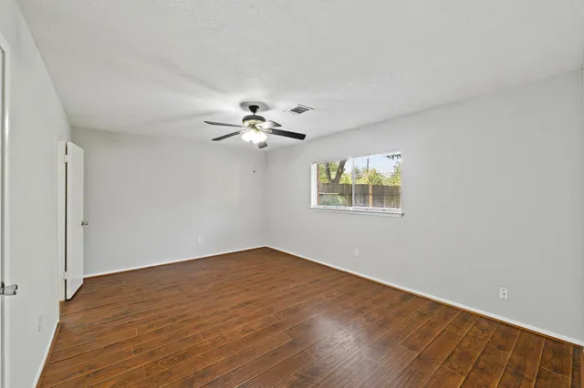 a view of an empty room with a window and wooden floor