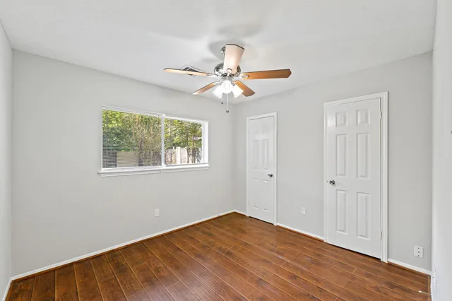 a view of an empty room with window and wooden floor