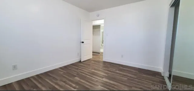 a view of an empty room with wooden floor and closet