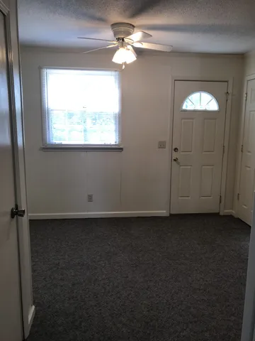 an empty room with windows and fan