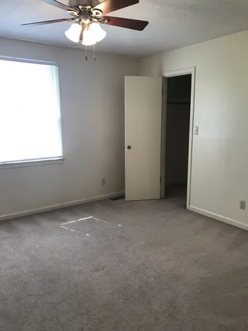 an empty room with a chandelier fan and windows