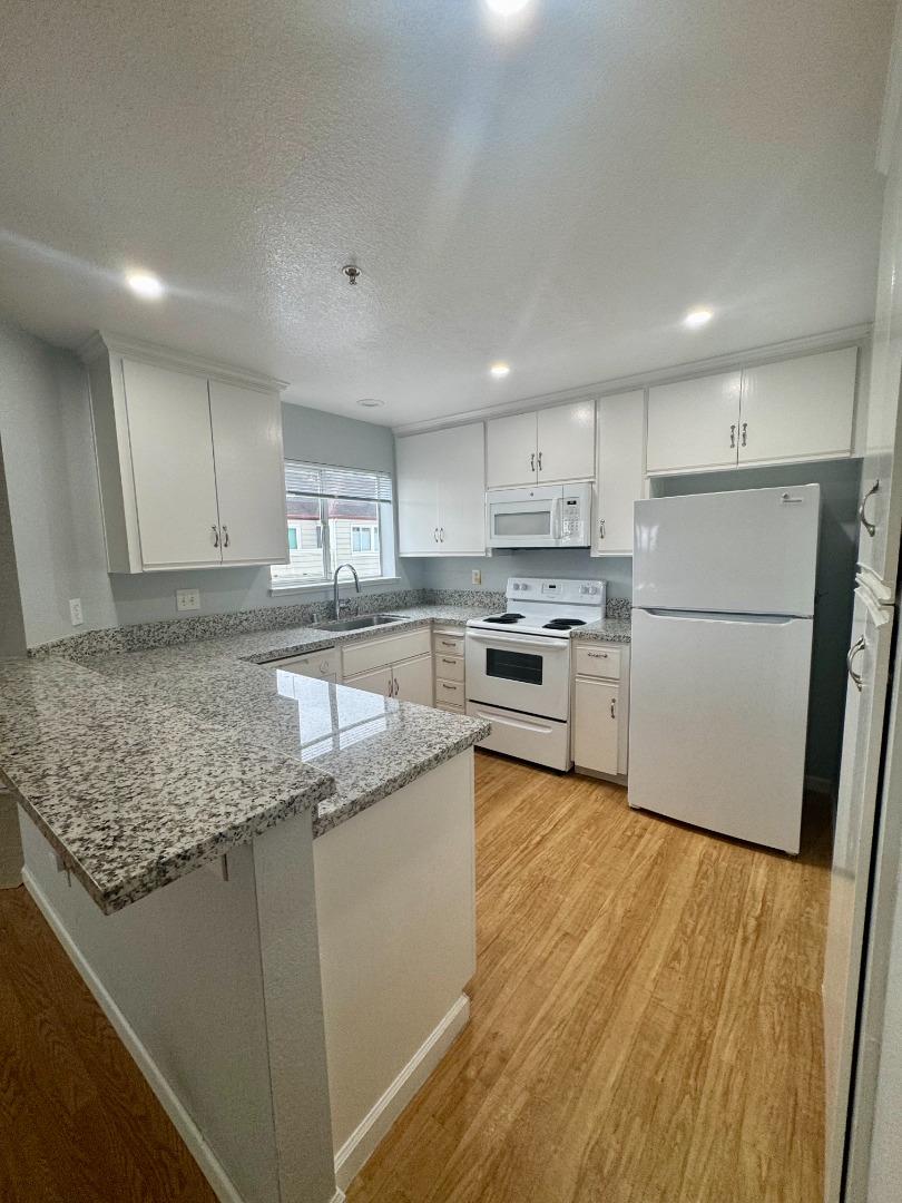 741 Pointe Pacific Drive, Unit 10 Daly City, CA 94014 - Photo 6 of 24 a kitchen with granite countertop a refrigerator a sink a stove a microwave and island