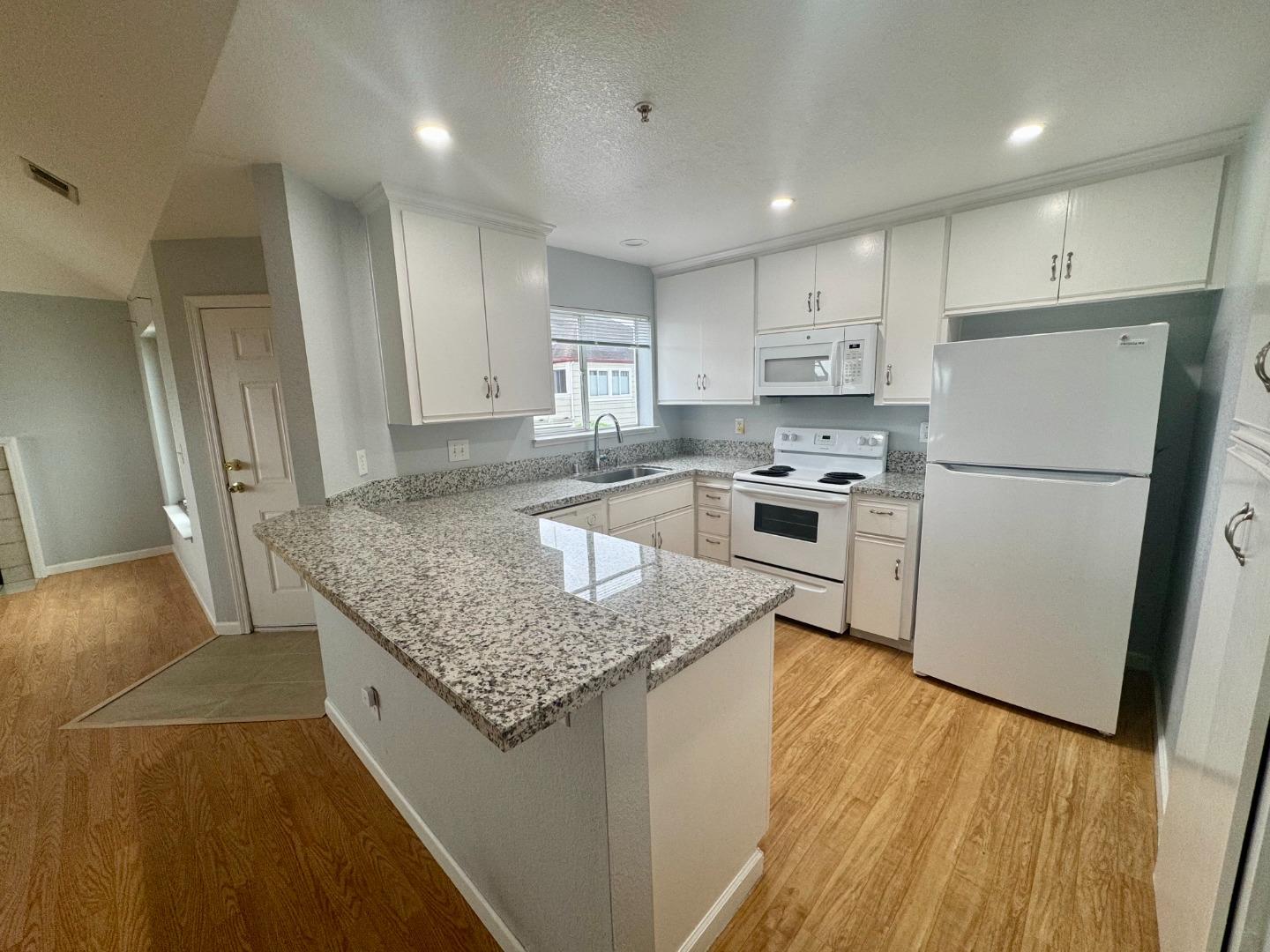 741 Pointe Pacific Drive, Unit 10 Daly City, CA 94014 - Photo 7 of 24 a kitchen with stainless steel appliances granite countertop a refrigerator a stove a sink dishwasher and a refrigerator with wooden floor