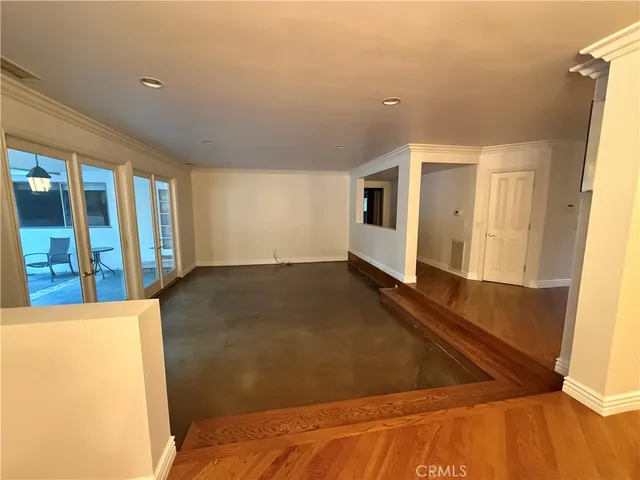 a view of a big room with wooden floor and windows