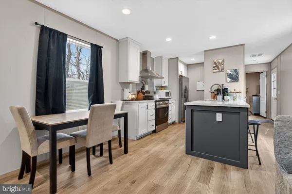 a kitchen with stainless steel appliances granite countertop a table chairs sink refrigerator and cabinets