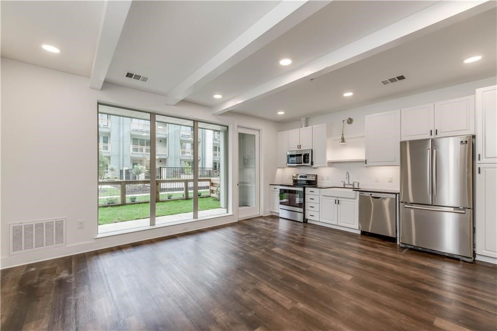a kitchen with stainless steel appliances a refrigerator a stove top oven and a large window