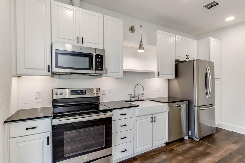4704 Sunset Trail, Unit 3102 Austin, TX 78745 - Photo 11 of 40 a kitchen with cabinets stainless steel appliances a sink and wooden floor