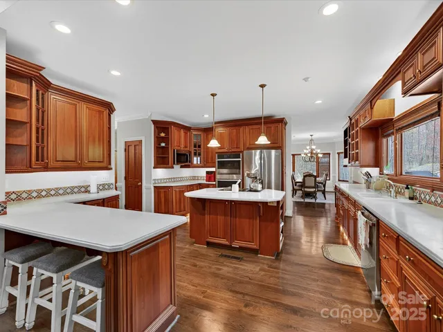 a kitchen with stainless steel appliances kitchen island granite countertop a table chairs and a refrigerator