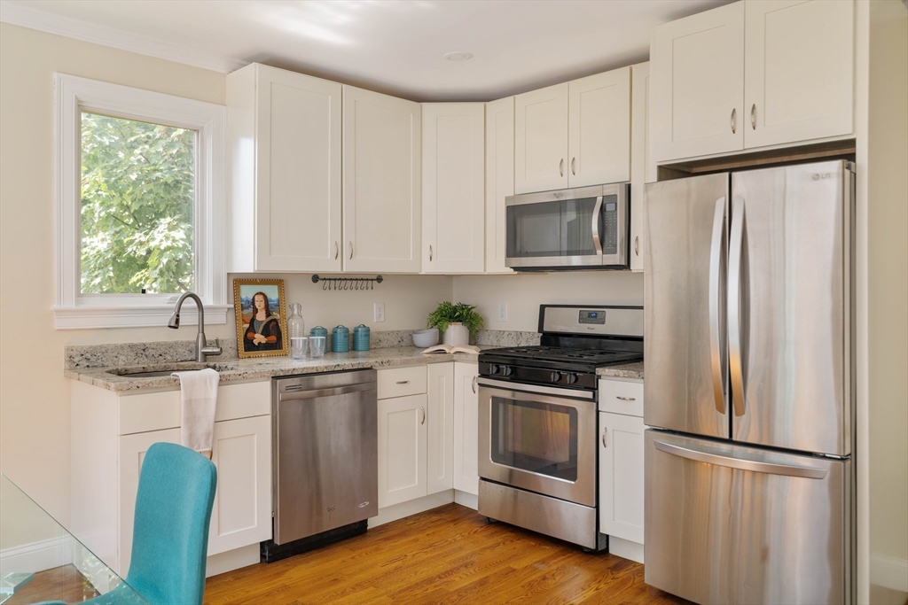 16 Partridge Avenue Somerville, MA 02145 - Photo 9 of 32 a kitchen with white cabinets white stainless steel appliances and wooden floors