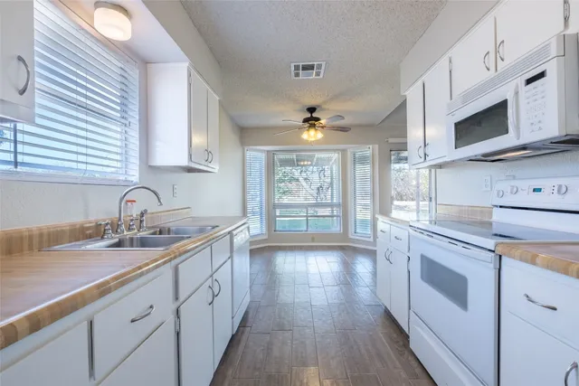 a kitchen with granite countertop white cabinets and white appliances