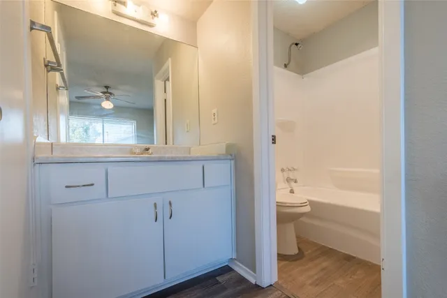 a bathroom with a granite countertop sink a toilet and shower