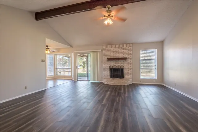 a view of an empty room with a fireplace and wooden floor