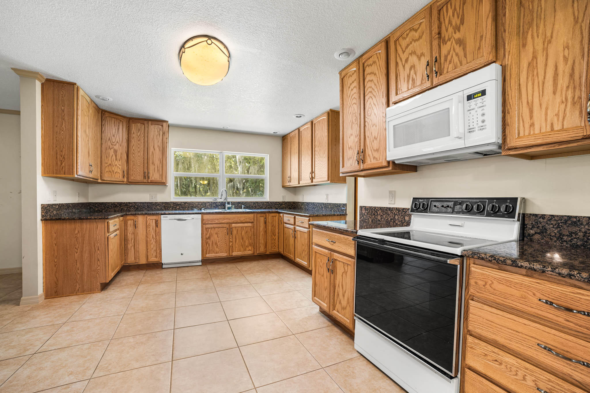 409 Southwest 15th Street Okeechobee, FL 34974 - Photo 7 of 14 a kitchen with stainless steel appliances granite countertop a stove sink and cabinets
