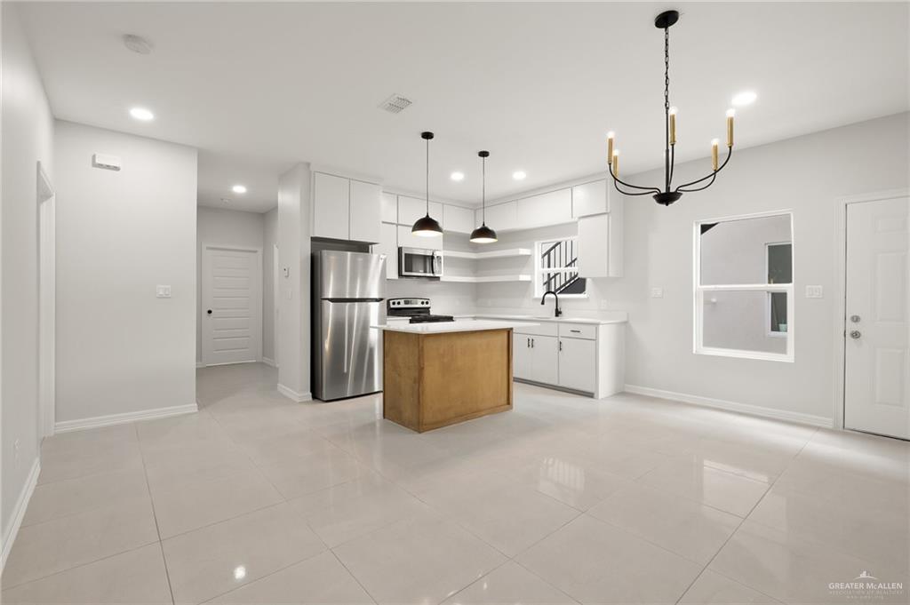 4217 Hummingbird Avenue McAllen, TX 78504 - Photo 11 of 15 Kitchen featuring white cabinets, appliances with stainless steel finishes, open shelves, a chandelier, and light tile patterned floors