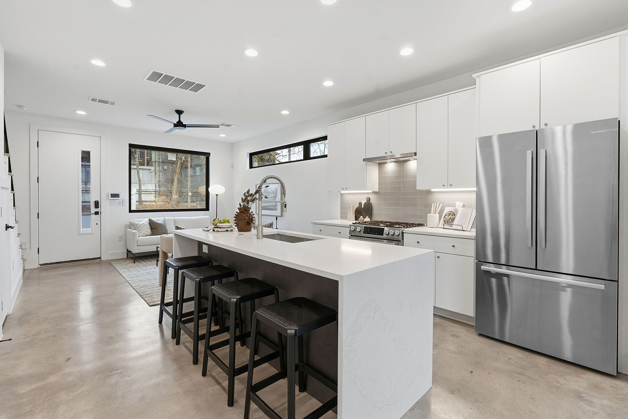 2411 Santa Rosa Street, Unit A Austin, TX 78702 - Photo 14 of 24 Kitchen featuring stainless steel appliances, white cabinetry, an island with sink, a breakfast bar, and finished concrete flooring