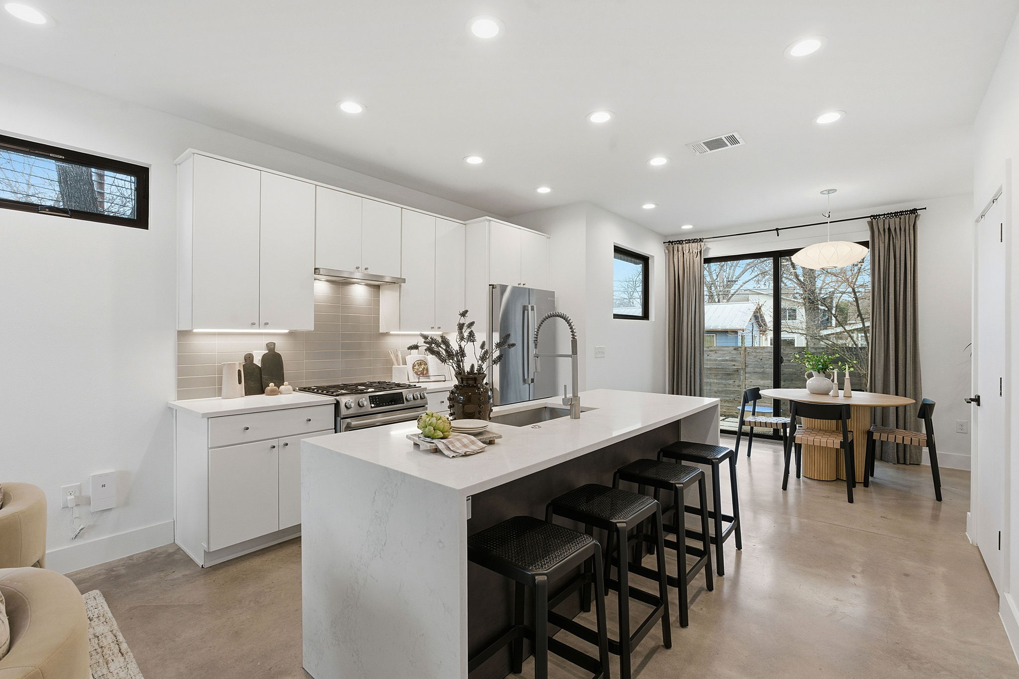 2411 Santa Rosa Street, Unit A Austin, TX 78702 - Photo 15 of 24 Kitchen with white cabinetry, a kitchen breakfast bar, stainless steel appliances, finished concrete flooring, and a center island with sink
