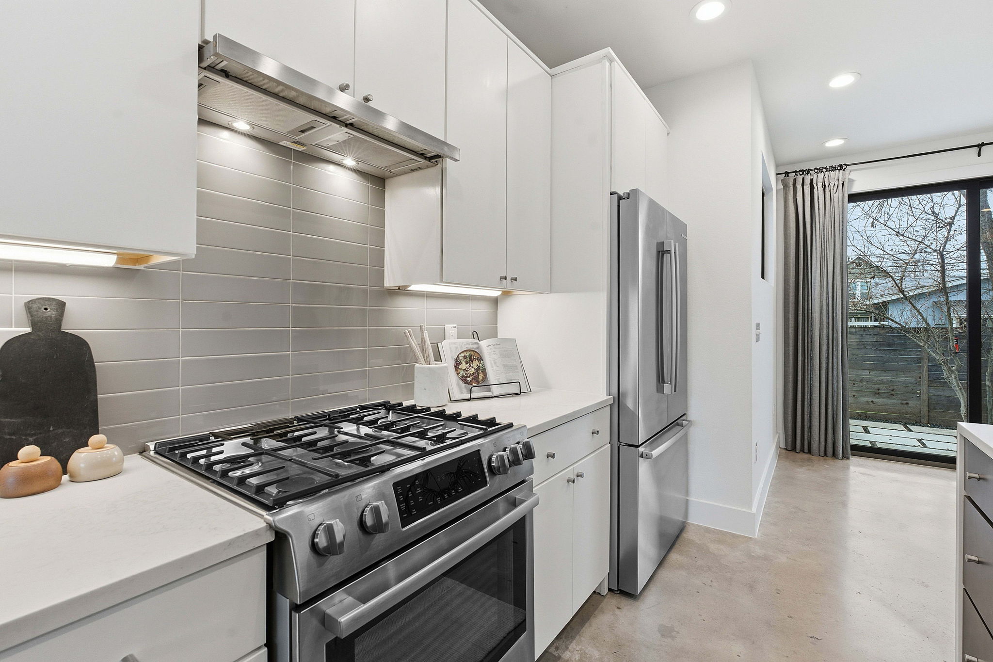 2411 Santa Rosa Street, Unit A Austin, TX 78702 - Photo 17 of 24 Kitchen with stainless steel appliances, extractor fan, concrete flooring, white cabinets, and backsplash