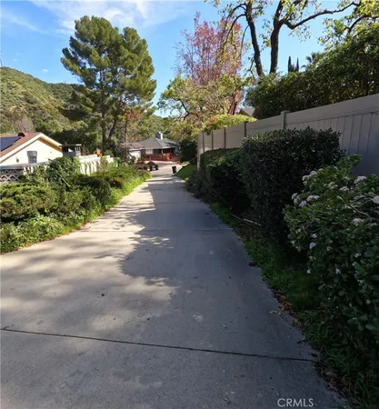 a view of a street with flower plants and wooden fence