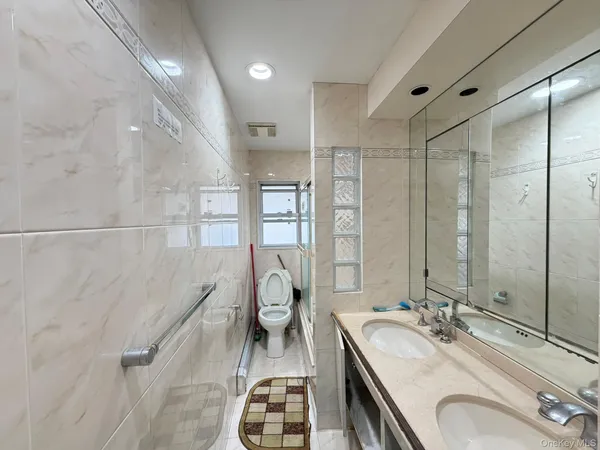 a spacious bathroom with a granite countertop double vanity sink a mirror and a shower