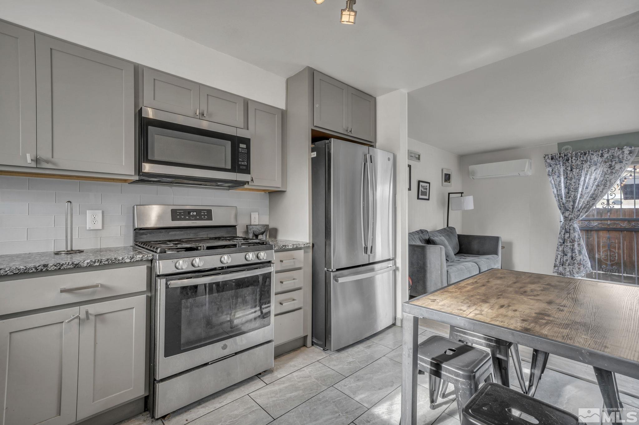 112 Smithridge Reno, NV 89502 - Photo 3 of 37 a kitchen with stainless steel appliances granite countertop a stove a refrigerator a microwave a sink a dining table and chairs