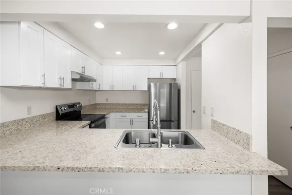 a kitchen with stainless steel appliances granite countertop a sink refrigerator and cabinets