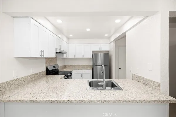 a kitchen with stainless steel appliances granite countertop a sink refrigerator and cabinets