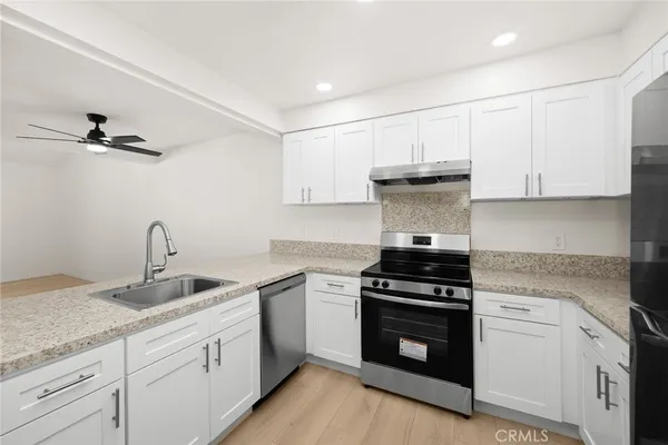 a kitchen with granite countertop white cabinets and stainless steel appliances
