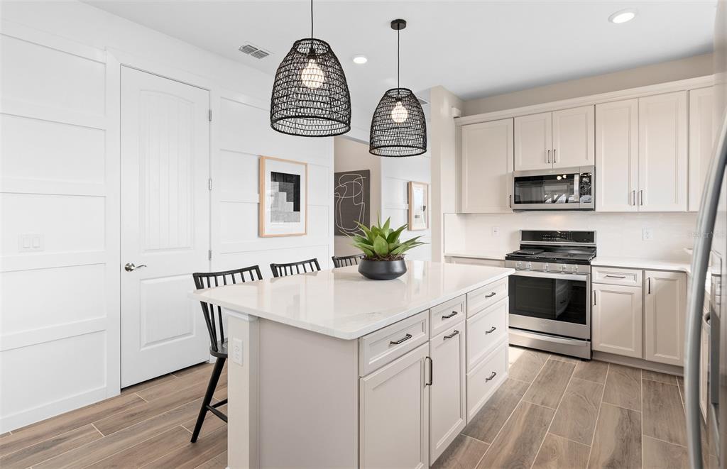 2370 Lily Bloom Road St. Cloud, FL 34771 - Photo 5 of 22 a kitchen with stainless steel appliances a white table chairs and a wooden floor