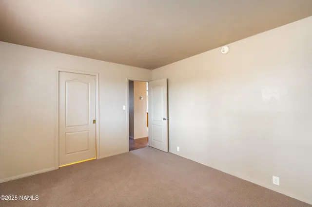 an empty room with wooden floor chandelier fan and windows