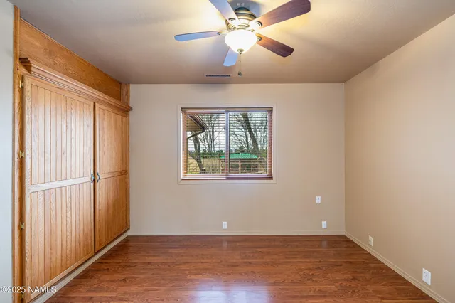 an empty room with windows and chandelier fan