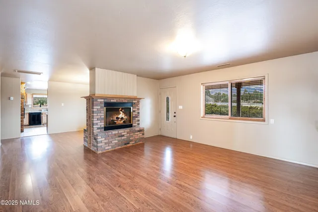 a view of an empty room with wooden floor and a fireplace