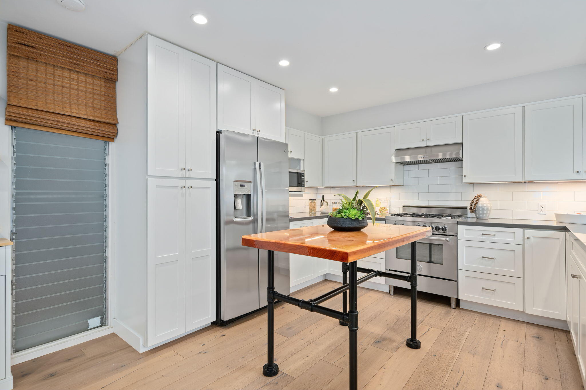 5 Fellowship Circle Santa Barbara, CA 93109 - Photo 7 of 32 a kitchen with stainless steel appliances white cabinets and wooden floor