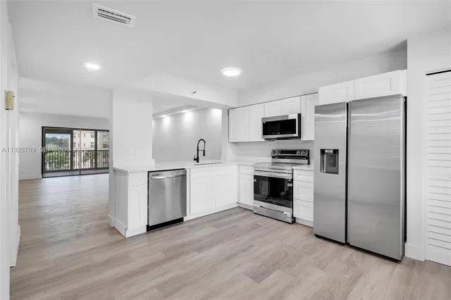 a kitchen with a refrigerator stove and wooden floor