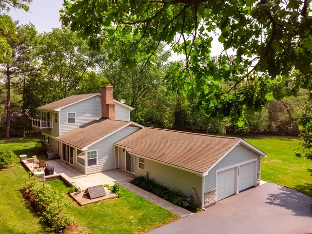a aerial view of a house in a big yard with large trees