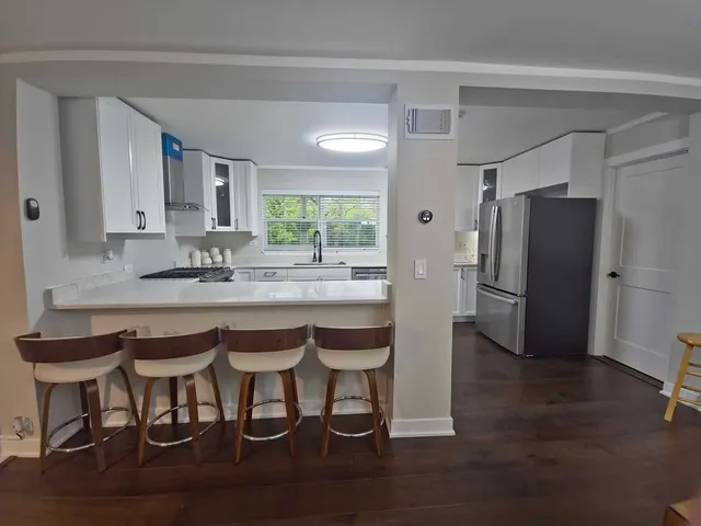 a kitchen with stainless steel appliances granite countertop a table chairs refrigerator a sink and dishwasher